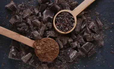 Picture of cacao beans being scooped up by spoons.