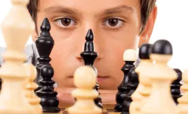 A chess player is looking at the chessboard