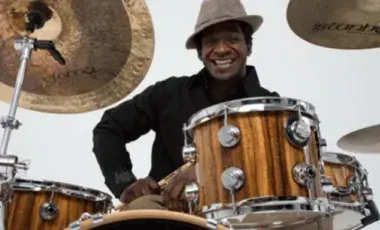 A smiling man sitting behind a drum set. 