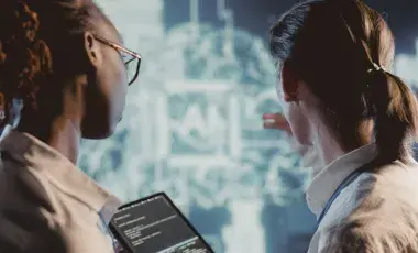 Two people looking at glowing image with Ai inside of a square