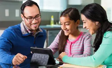 a man, a woman and a tween girl looking at a tablet