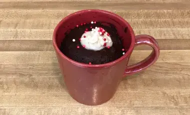 A mug cake in a red mug, topped with whipped cream