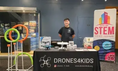 Man standing behind a table with drones