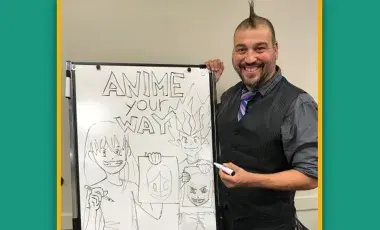 Artist Carlos Nieto III standing next to his anime drawings.