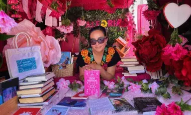 Ariadna Sánchez Hernández holding her book Visitas inesperadas, surrounded by flowers and books