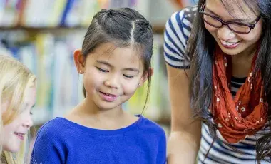 Two children listen to a STAR reader at the library.