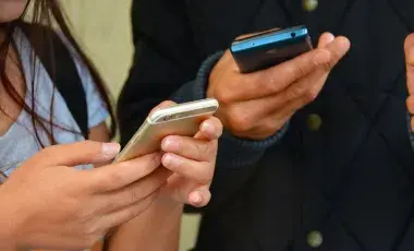 Two people holding two cellphones next to each other