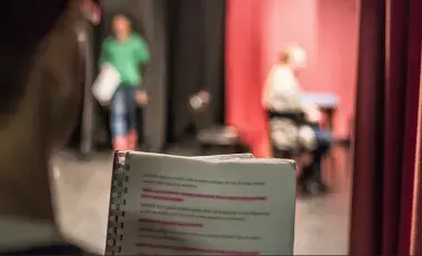person with highlighted passages in a play with two other people