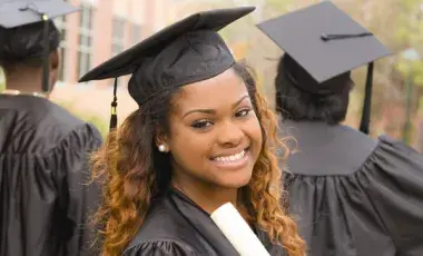 graduate in cap and gown, holding a diploma