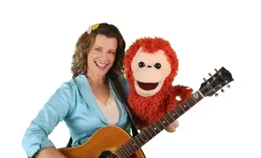 Alana holding a guitar and monkey puppet