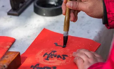 person writing in Chinese calligraphy