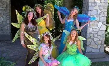 A performance group of five women dressed as colorful fairies. 