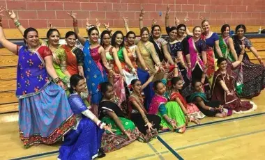 group of dancers dressed in colorful Indian saris pose with arms outstretched