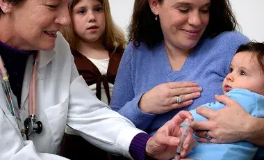baby receiving a shot by doctor with parents