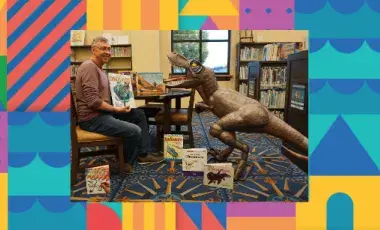Presenter, Paul and his prehistoric pal, a dinosaur life-sized figure in a library surrounded by dinosaur children books.