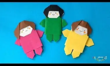 three flat origami dolls with pink green and yellow outfits on 