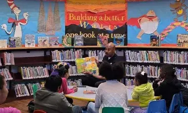 Police officer is reading a book to a group of children