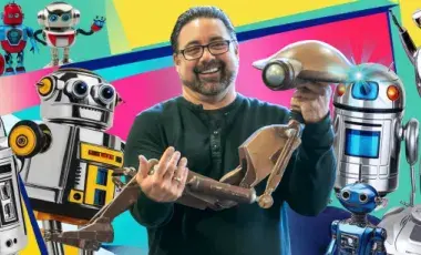 Paul Thompson holding a droid robot, surrounded by other robots