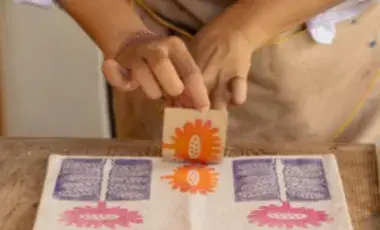 Person removing a stamp-stencil from canvas material.