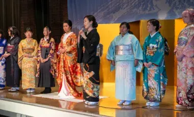 Ten women of various ages onstage dressed in kimonos.