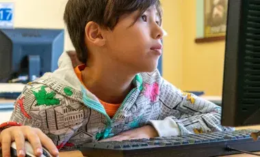 A young boy uses a desktop computer.