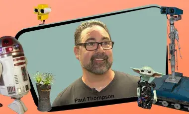 Man on screen surround by robots he built himself.
