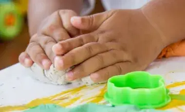 hands doing sensory play with play dough