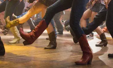 a photo of a group of people line dancing showing legs and feet only