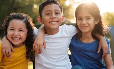 3 children with arms around each other's shoulders