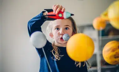 A young girl playing with a toy rocket and planets