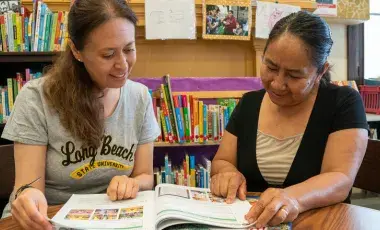 Volunteer tutor is assisting to adult learner.