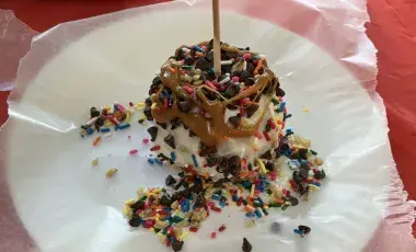 Chocolate and caramel apple with cookie crumbs, nuts, chocolate chips, and sprinkles