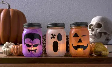 three mason jars decorated to look like a vampire, ghost, and jack o lantern