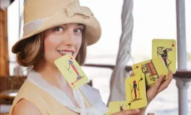Katrina holding one playing card in her teeth and a bridge spread of other cards between two hands