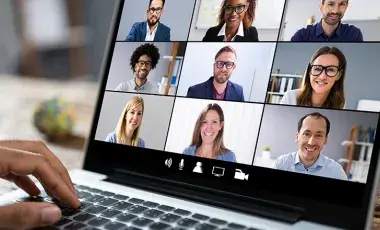 laptop open with video conference showing nine people in squares. 