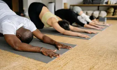 4 people doing yoga in downward dog position 