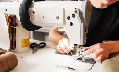 A person adjusts thread on a sewing machine.