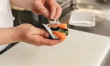 chef hands cooking sushi with rice salmon and nori