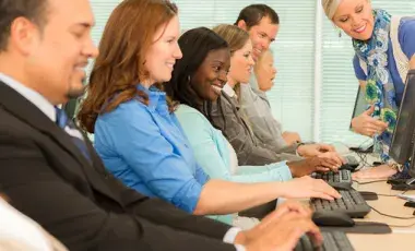 Adults sitting and learning to use computers