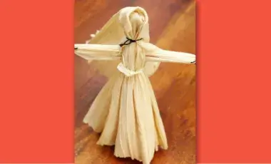 corn husk doll standing on a table