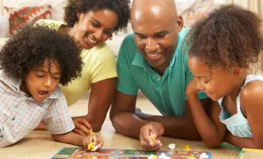 Parents and their two children are playing a board game