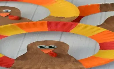 Paper plate with alternating red, yellow, orange colors and a cut out of a brown colored turkey.