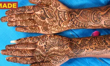 Two outstretched arms covered in black henna tattoos