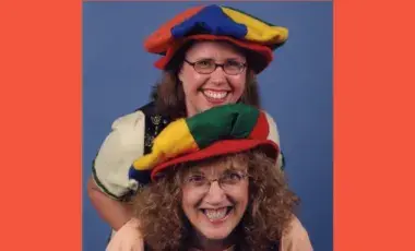 Two performers are wearing funny hats