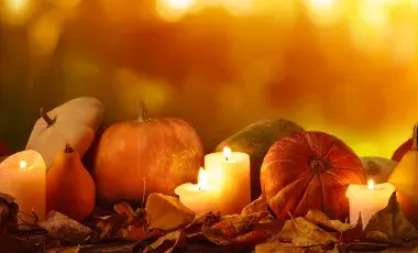 Autumn night scene with pumpkins, squash and lighted candles on fallen leaves