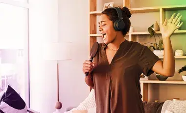 young brown skinned women holdng a hairbrush as if she were singing into it.