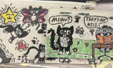 Image of two pouches that have drawings of cats. 