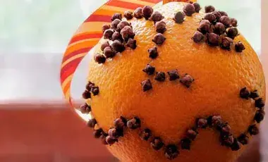 an orange (the fruit) studded with cloves in a pattern that resembles of face