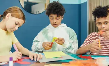 Three children cut out pieces of colorful paper. 