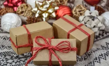 Brown packages tied with red string, with holiday decorations in the background, Image by Monika from Pixabay